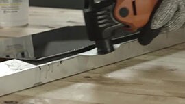 Video still of a worker using an oscillating tool to separate a metal plate bonded to a metal bar