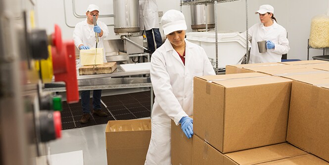 Three workers wit boxes in a packaging facility
