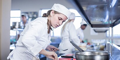 Mulher cozinhando em restaurante.
