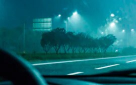 Rodovia molhada sendo vista de dentro de um carro olhando diretamente para a estrada bem demarcada.