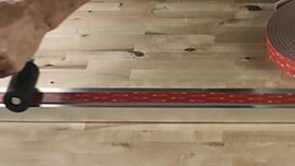 Video still of a person using a J-roller to ensure even pressure is applied to the tape