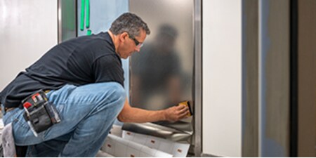 Funcionário instalando um acabamento arquitetônico em uma porta.
