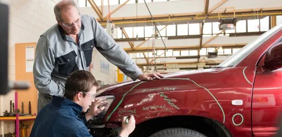 Dois homens fazendo reparo em um carro.

