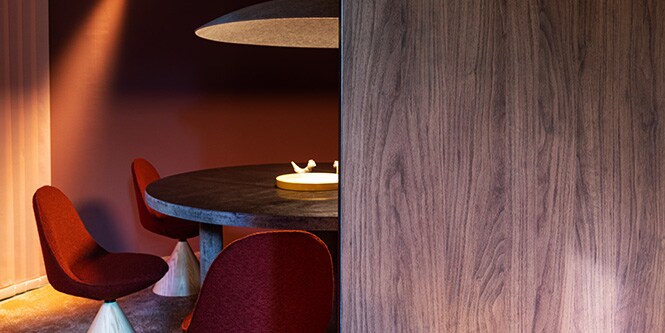 Sala de jantar com mesa redonda e revestida com Acabamento Arquitetônico 3M DI-NOC metálico, além de paredes com acabamentos arquitetônicos em cor fosca e madeira escura.
