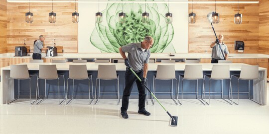 A restaurant worker cleans a floor with a mop.
