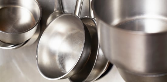 dishwasher cleaning a pan at a commercial sink in the back of the house.
