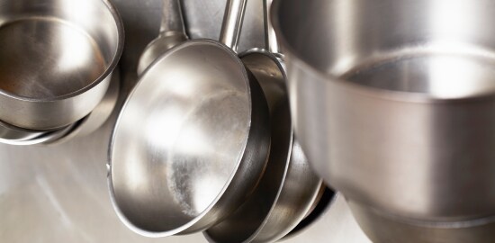 dishwasher cleaning a pan at a commercial sink in the back of the house.
