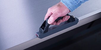 Image of someone using an L-abrader tool to lightly abrade a surface
