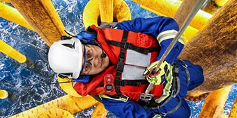 Worker hanging in safety harness over water wearing clear, fog-free protective eyewear, hardhat, safety vest and hearing protection
