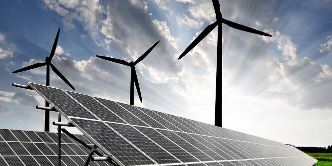 Painéis solares em primeiro plano e três turbinas eólicas ao fundo sob um céu parcialmente nublado, representando a geração de energia renovável.
