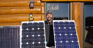 3M scientist Tim Hebrink holding the solar panels that have helped him generate about 80 percent of his home’s energy.