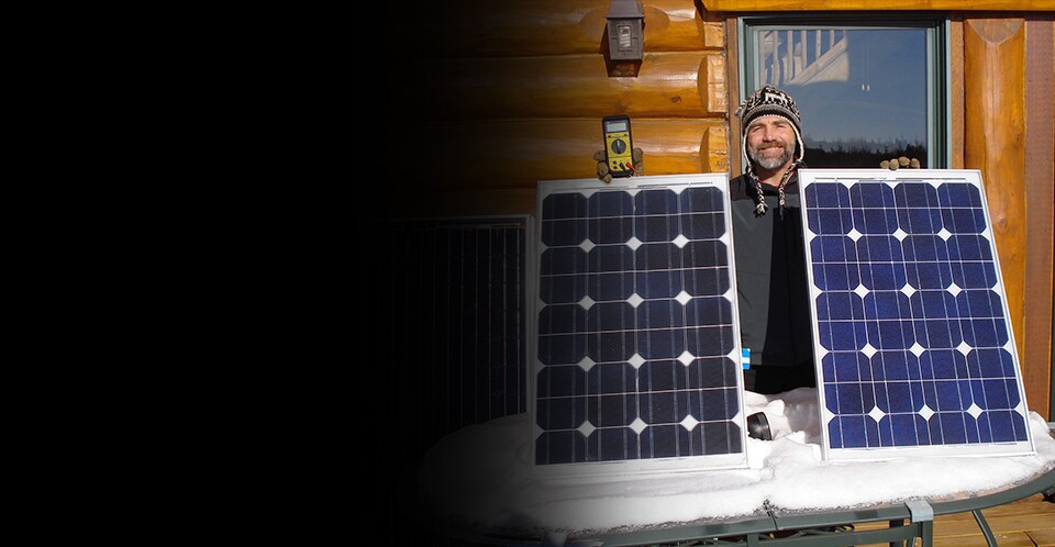 3M scientist Tim Hebrink holding the solar panels that have helped him generate about 80 percent of his home’s energy.