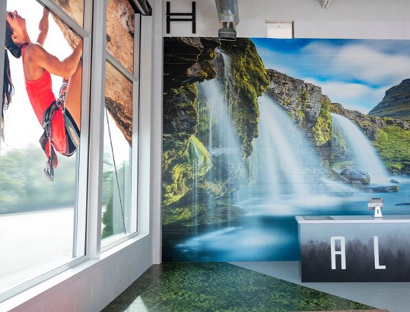 Interior de uma loja de roupas esportivas com uma parede decorada com a imagem de uma cachoeira.