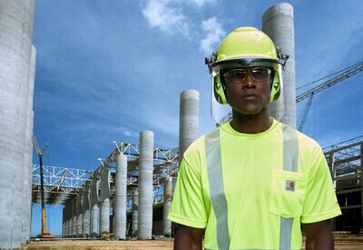 Trabalhador de construção civil utilizando capacete, óculos de proteção e protetores auditivos 3M.
