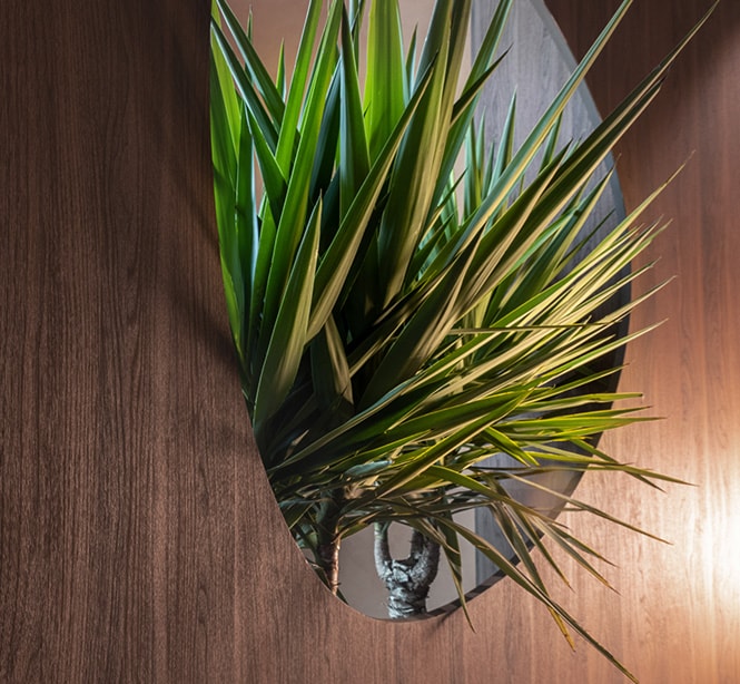 Interior moderno de um saguão de hotel apresentando Acabamentos Arquitetônicos 3M metálicos e em pedra, além de uma janela repleta de plantas.