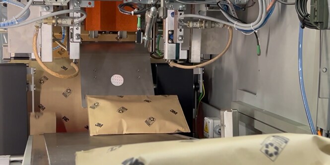 Embalagem de papel passando por uma máquina automatizada.
