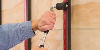 Image of someone using a J-roller to apply pressure to tape on a metal post
