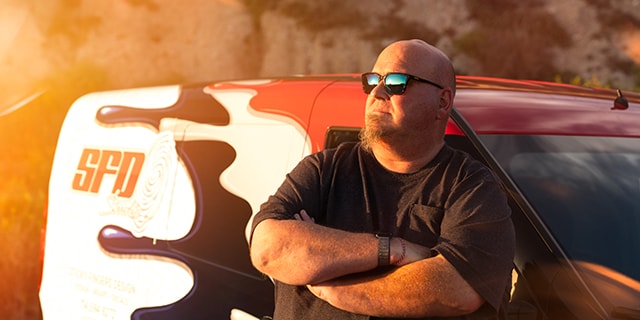 John Sticky Fingers Meehan, fundador da SFDS, encostado em um carro coberto com IJ280.
