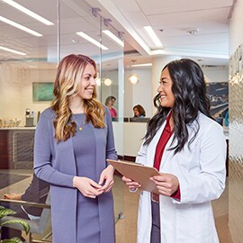 Two females talking in an office, one woman is a professional the other is a doctor.