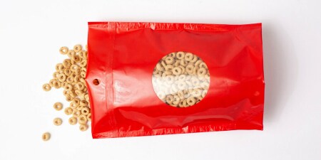 Image showing cereal spilled from a red package demonstrating the 3M™ Grip Lock Strip easy open-and-close performance 
