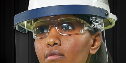 worker wearing safety glasses and a faceshield attached to hard hat
