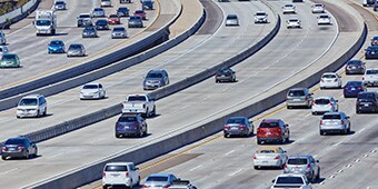 Dozens of cars drive on several neighboring highways, demonstrating the need for durable road markings.
