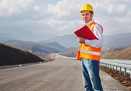 Trabalhador de manutenção de estradas de pé em uma estrada sem marcação.