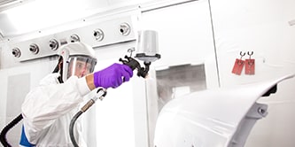 Técnico  aplicando primer em um carro para pintura.
