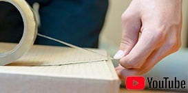 Imagem de uma pessoa iniciando a selagem com fita em uma caixa de papelão ondulado.
