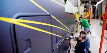 Image of workers masking the side of a recreational vehicle
