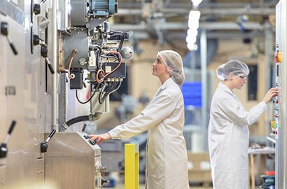 Workers operate equipment in food production facility.