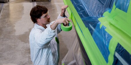 Image of a worker masking off a panel on a boat
