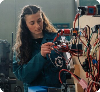 A girl student working on a machine in a classroom.
