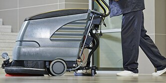 Funcionário usando uma máquina de limpeza de pisos para polir um piso.
