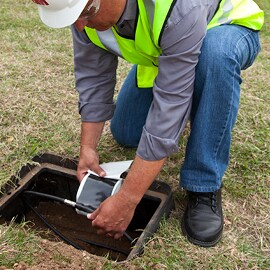 Electrician crouching over and taping a slice  for a subterranean cable with electrical tape.