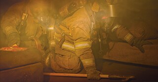 Firefighters crawling through a smoke-filled building