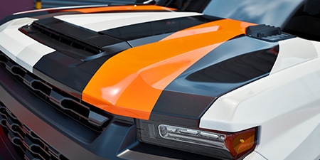 Close-up do capô de um caminhão coberto com reentrâncias profundas e curvas compostas.
