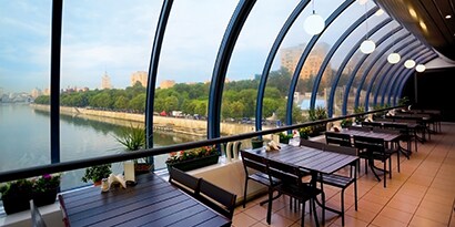 A restaurant with large, curved windows looks out onto a body of water.
