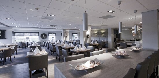 Salão de restaurante com várias mesas organizadas e limpas.
