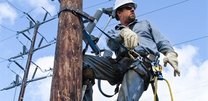 Workman on power pole wearing work positioning belt
