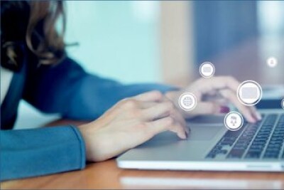 Imagem de mãos femininas digitando em um notebook, com ícones espalhados pela imagem que exibem desenhos ligados à internet e tecnologia.
