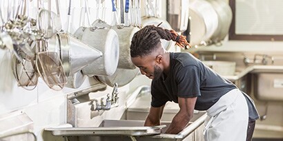 A man washing dishes in a commercial kitchen
