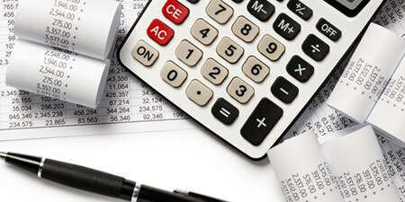 Uma calculadora cercada por recibos impressos e gráficos.
