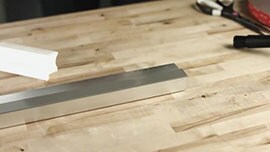 Video still showing a metal bar with 3M™ VHB™ Tape applied and the liner removed, a hand applicator, scissors and a tape roll
