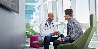 Médico conversando com paciente em saguão iluminado.
