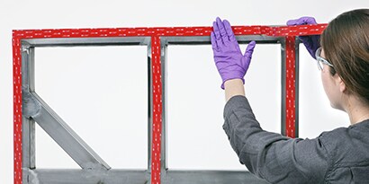 Technician applies industrial adhesive tape to a panel to frame assembly
