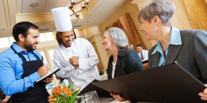Chef e clientes interagindo em um restaurante.
