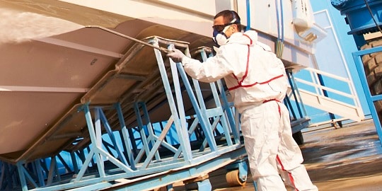 Respirador 3M protegendo um homem de gases e vapores durante a limpeza de um barco
