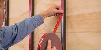 Image of a worker applying tape to a metal post by hand
