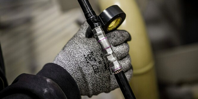 Trabalhador enrolando fita Super 33+ em uma emenda elétrica de formato irregular.
